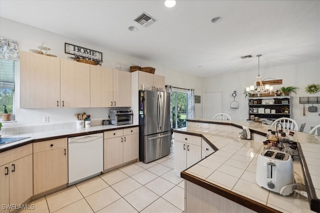 kitchen with stainless steel fridge, white dishwasher, tile counters, and a healthy amount of sunlight