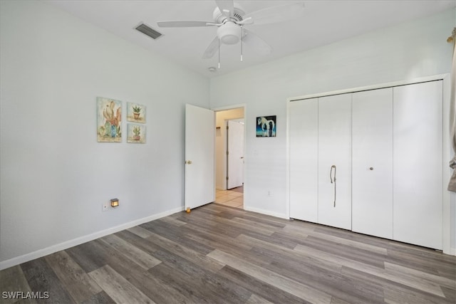 unfurnished bedroom featuring hardwood / wood-style floors, ceiling fan, and a closet