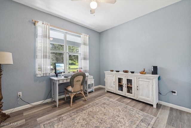 office with light wood-type flooring and ceiling fan