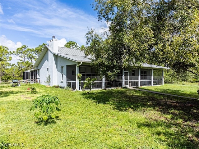 rear view of property with a yard and a sunroom