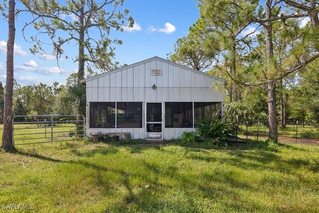 rear view of property with a lawn and a sunroom