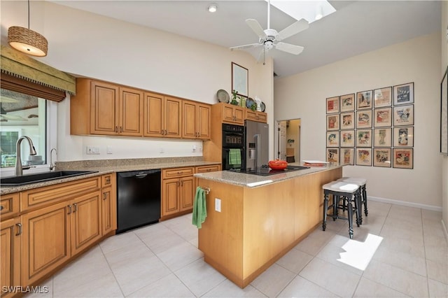 kitchen featuring sink, decorative light fixtures, a breakfast bar area, a kitchen island, and black appliances