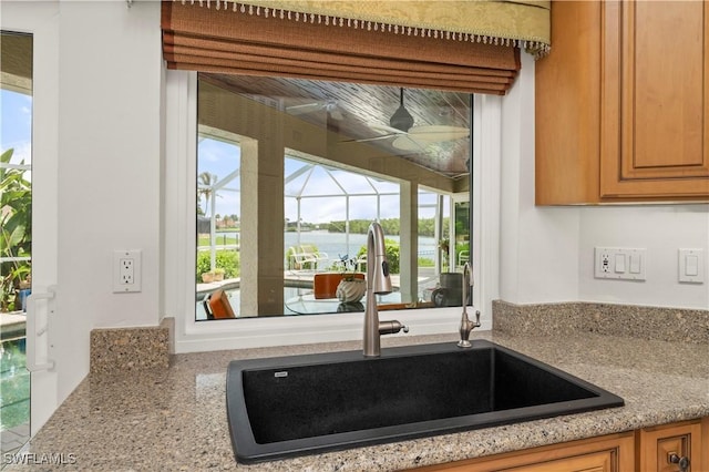 kitchen featuring sink, light stone counters, and a water view