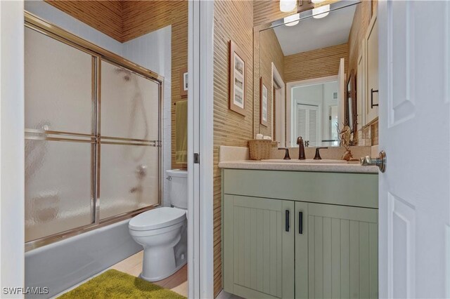 full bathroom featuring enclosed tub / shower combo, vanity, and toilet