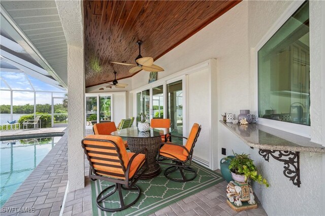 sunroom / solarium with lofted ceiling, wooden ceiling, a healthy amount of sunlight, and a water view