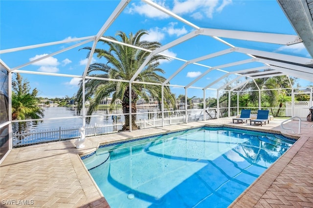 view of pool featuring a patio, a water view, and glass enclosure