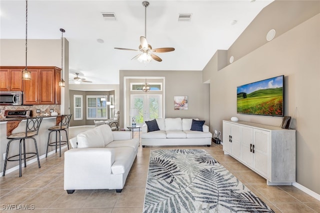 living room with light tile patterned floors, ceiling fan, and high vaulted ceiling