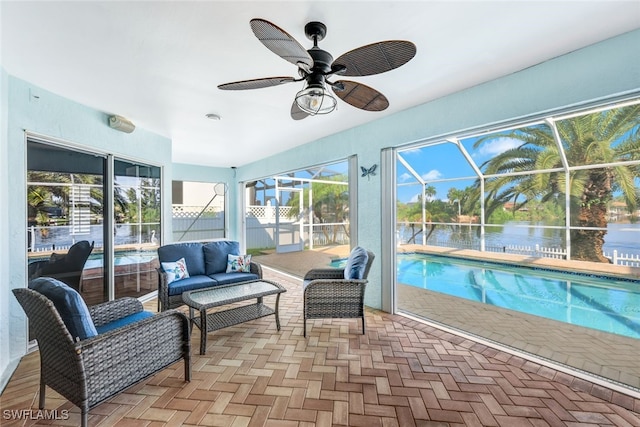 sunroom with ceiling fan and a water view