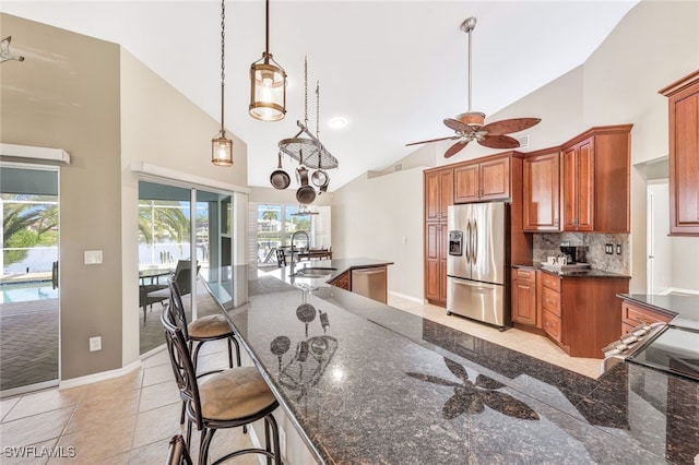 kitchen featuring appliances with stainless steel finishes, hanging light fixtures, high vaulted ceiling, ceiling fan with notable chandelier, and a breakfast bar area