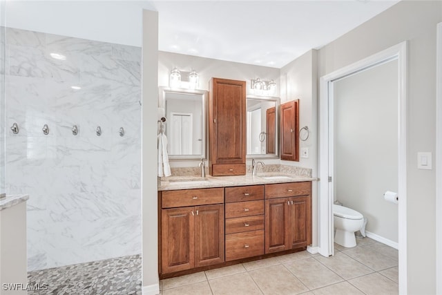 bathroom featuring vanity, tile patterned flooring, toilet, and tiled shower