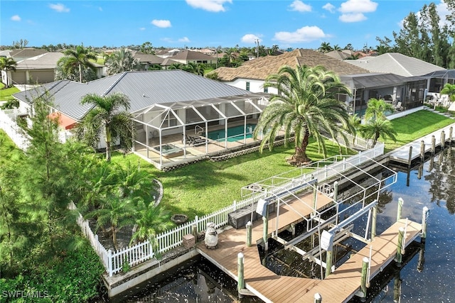 exterior space with a water view, glass enclosure, a patio area, and a lawn