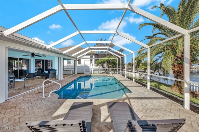 view of swimming pool featuring a patio, glass enclosure, and ceiling fan