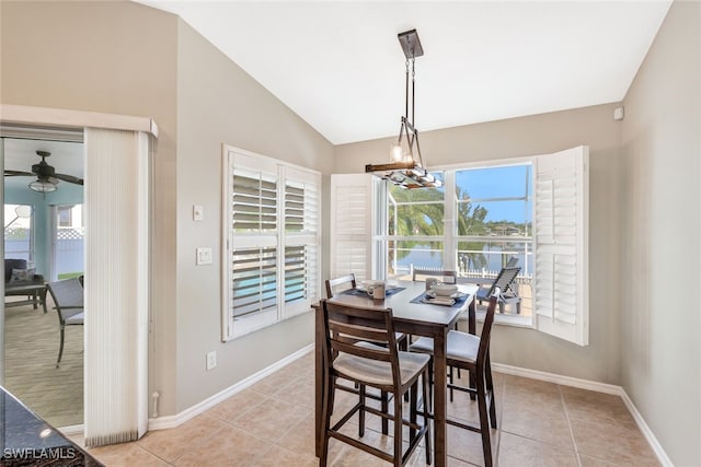 tiled dining room featuring ceiling fan with notable chandelier and lofted ceiling