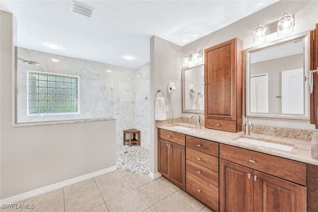 bathroom with a tile shower, tile patterned flooring, and vanity