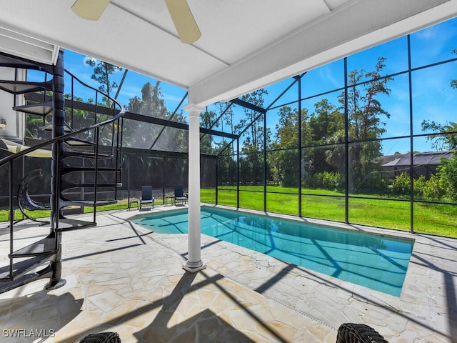 view of pool featuring ceiling fan, glass enclosure, a patio, and a lawn