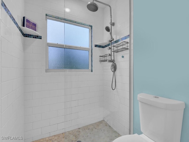 bathroom with a tile shower and toilet