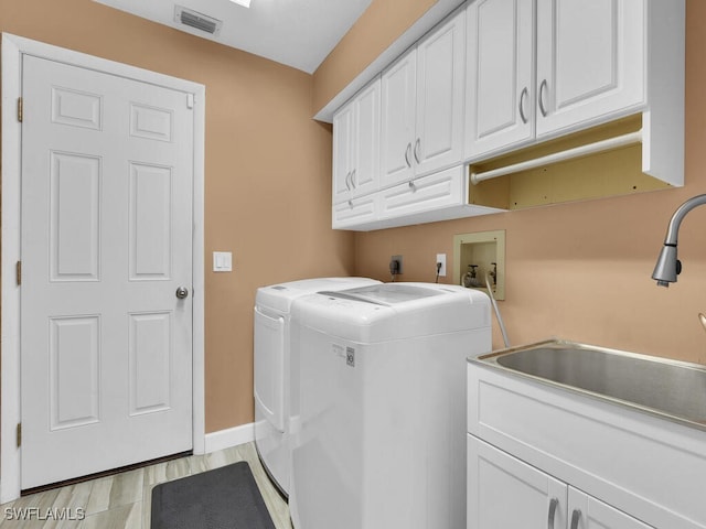 laundry room featuring cabinets, light hardwood / wood-style flooring, sink, and washer and dryer