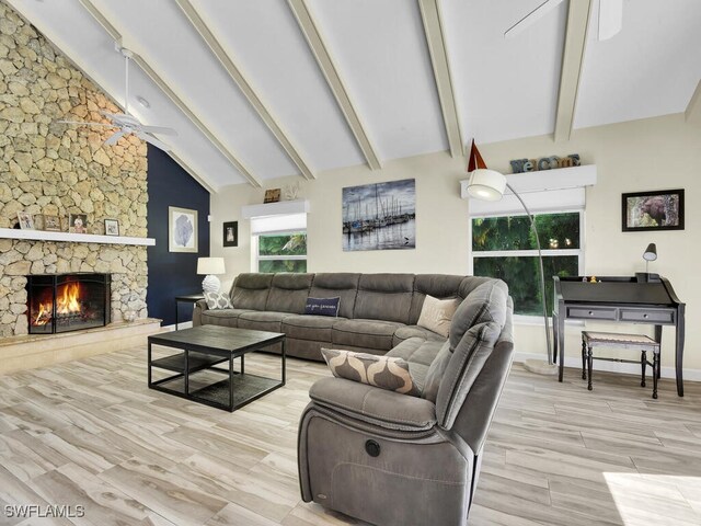 living room featuring high vaulted ceiling, a stone fireplace, beam ceiling, ceiling fan, and light hardwood / wood-style flooring