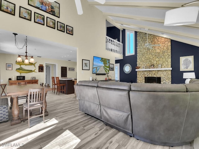 living room featuring light hardwood / wood-style floors, a fireplace, beamed ceiling, and high vaulted ceiling