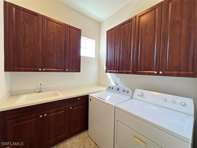 clothes washing area featuring washing machine and clothes dryer, cabinets, and sink