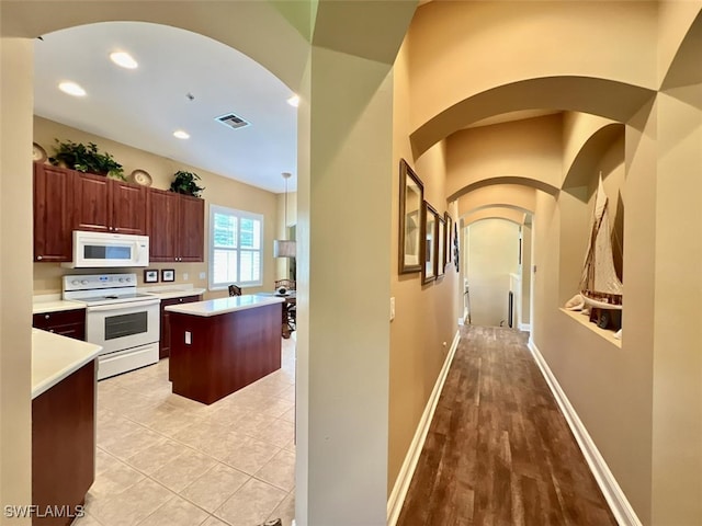 kitchen with white appliances, a center island, and light hardwood / wood-style floors