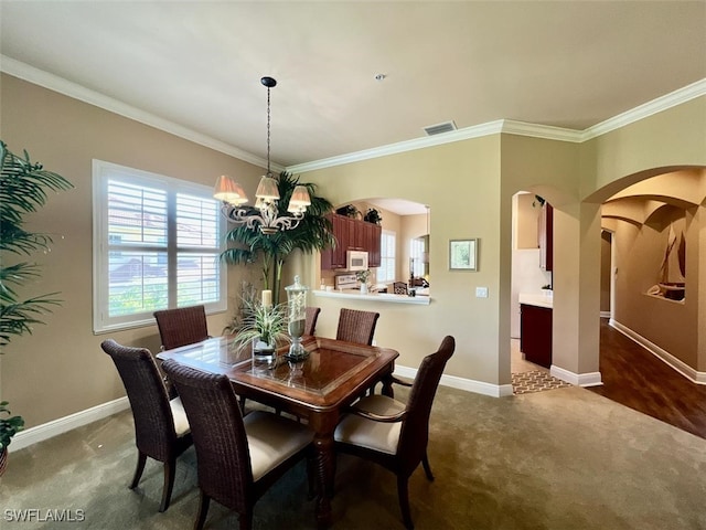 dining room with ornamental molding, dark colored carpet, and a notable chandelier