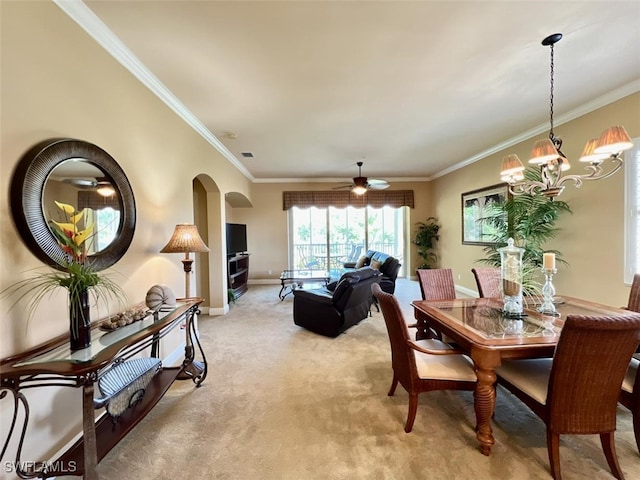 carpeted dining space with ornamental molding and ceiling fan with notable chandelier