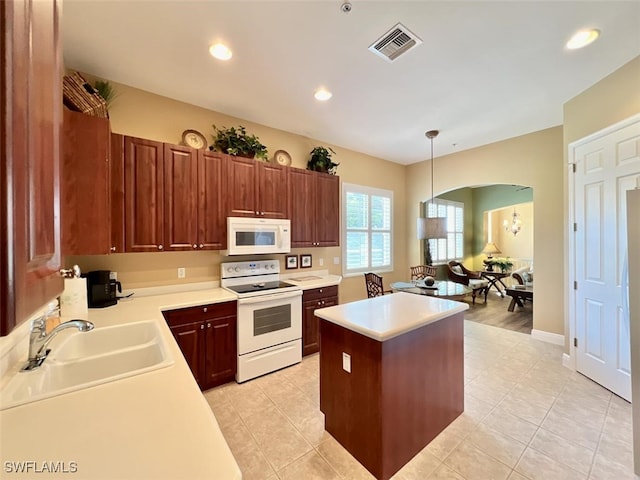 kitchen with a kitchen island, decorative light fixtures, white appliances, light tile patterned floors, and sink