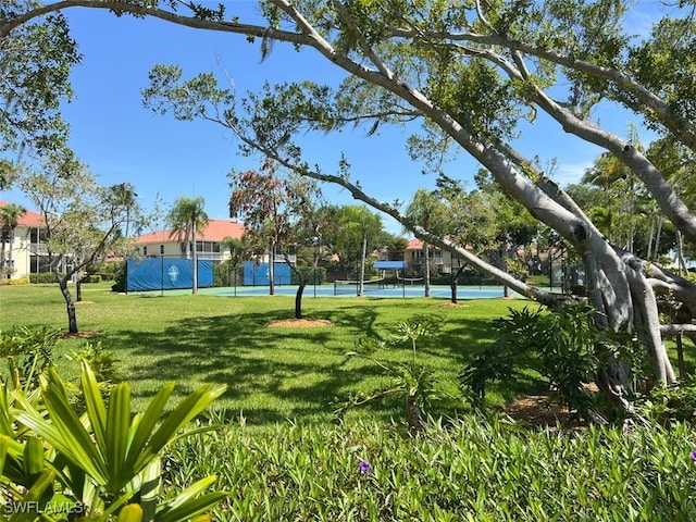 view of property's community with tennis court and a yard