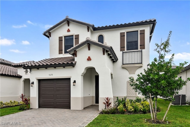 mediterranean / spanish house with a garage, a front lawn, and central AC