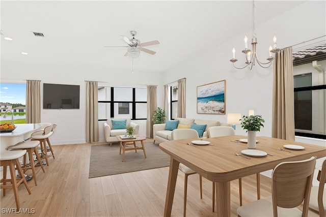 dining space featuring light hardwood / wood-style flooring and ceiling fan with notable chandelier