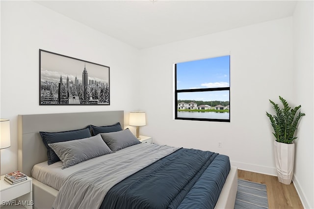 bedroom with wood-type flooring and a water view