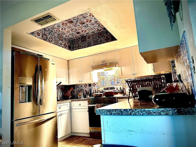 kitchen with hardwood / wood-style floors, stainless steel fridge, white cabinetry, backsplash, and electric range