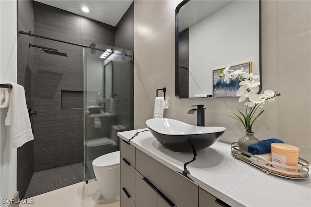 bathroom featuring vanity, toilet, a shower with shower door, and tile patterned floors