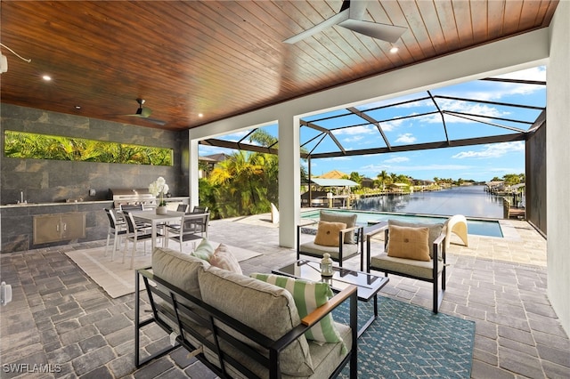 view of patio featuring a water view, ceiling fan, a lanai, and an outdoor hangout area