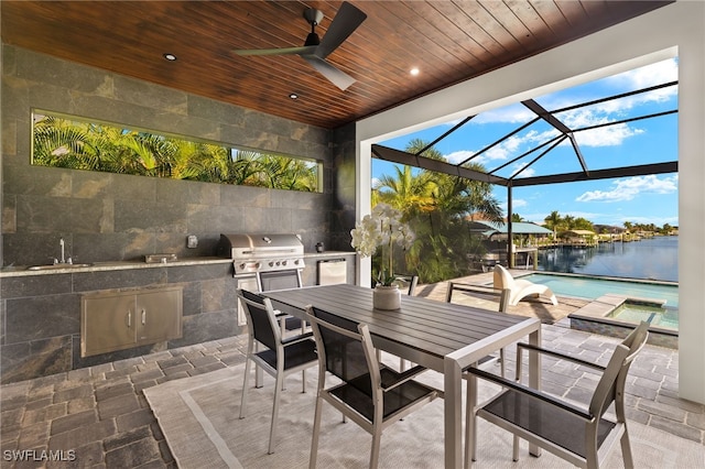 view of patio / terrace with area for grilling, grilling area, glass enclosure, ceiling fan, and a water view