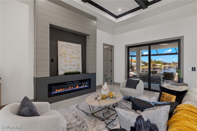 living room with ornamental molding, beamed ceiling, a water view, and a large fireplace