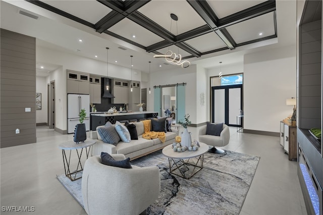 living room with a barn door, coffered ceiling, a chandelier, and beam ceiling