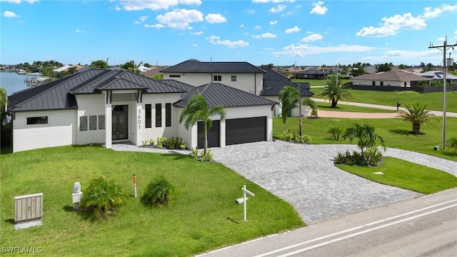 view of front of property with a garage, a water view, and a front lawn