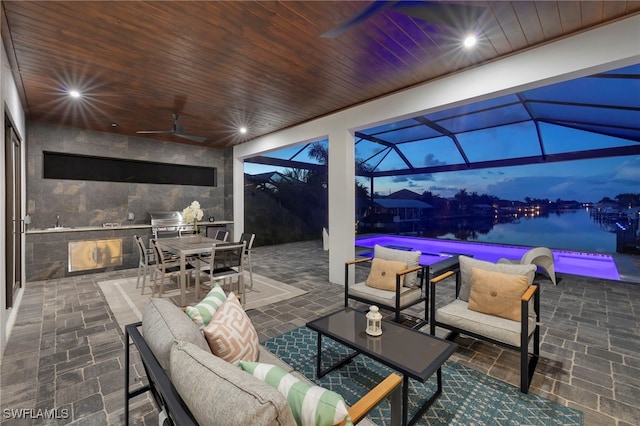 view of patio featuring a water view, ceiling fan, an outdoor hangout area, and a lanai