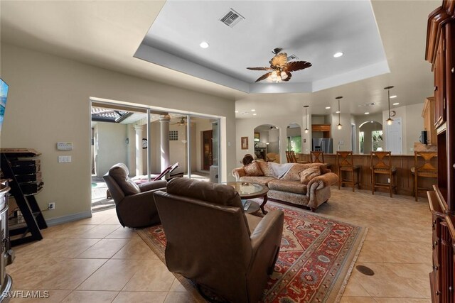 tiled living room featuring a tray ceiling and ceiling fan