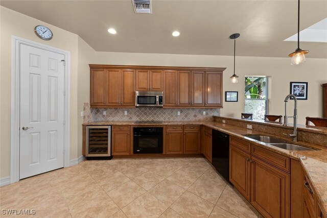 kitchen with black appliances, hanging light fixtures, sink, wine cooler, and light stone counters