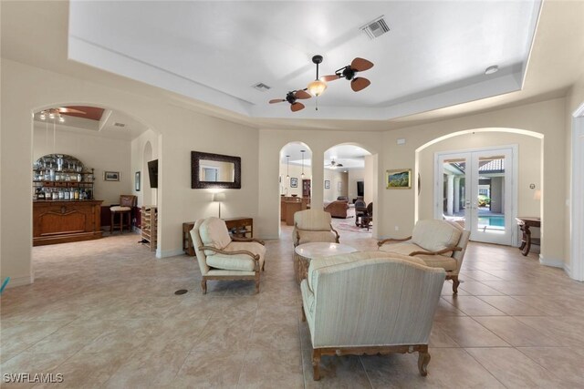 tiled living room featuring ceiling fan and a raised ceiling