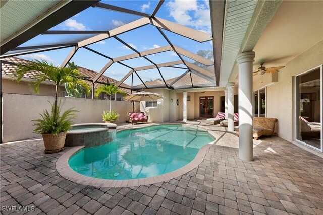 view of swimming pool with glass enclosure, ceiling fan, a patio, and an in ground hot tub