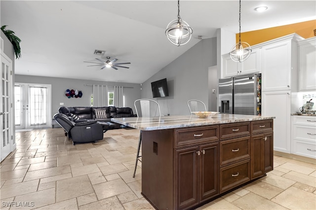 kitchen featuring stainless steel fridge, decorative light fixtures, ceiling fan, vaulted ceiling, and white cabinets