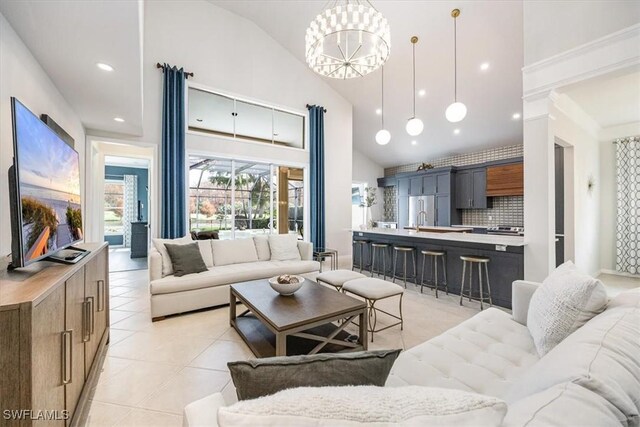 tiled living room featuring high vaulted ceiling and an inviting chandelier