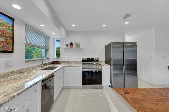 kitchen with light stone countertops, stainless steel appliances, sink, white cabinets, and light tile patterned flooring