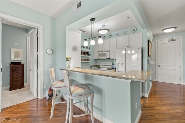 kitchen featuring kitchen peninsula, a kitchen breakfast bar, decorative light fixtures, white cabinets, and white appliances