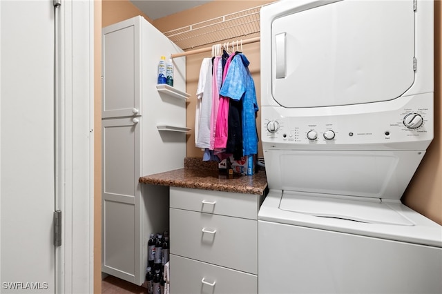 washroom featuring cabinets and stacked washer / drying machine