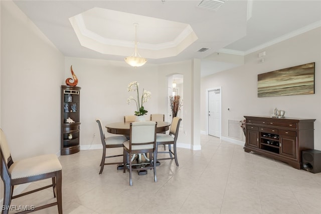 dining room featuring baseboards, visible vents, arched walkways, crown molding, and a raised ceiling